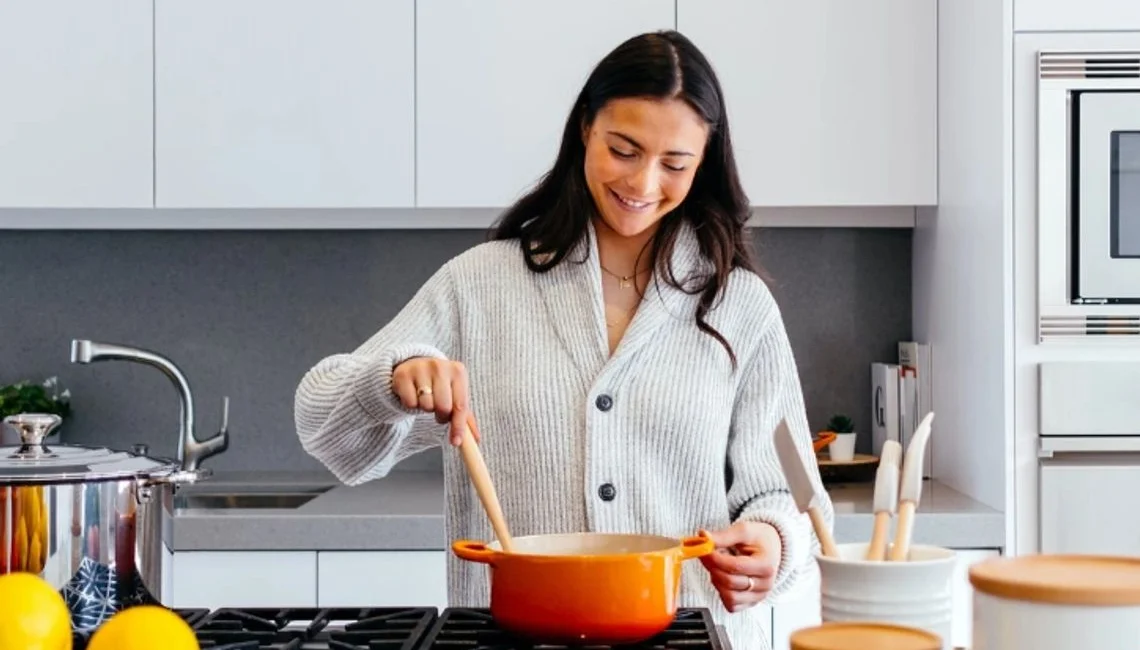 A woman cooking on a gas hob in a bright modern kitchen