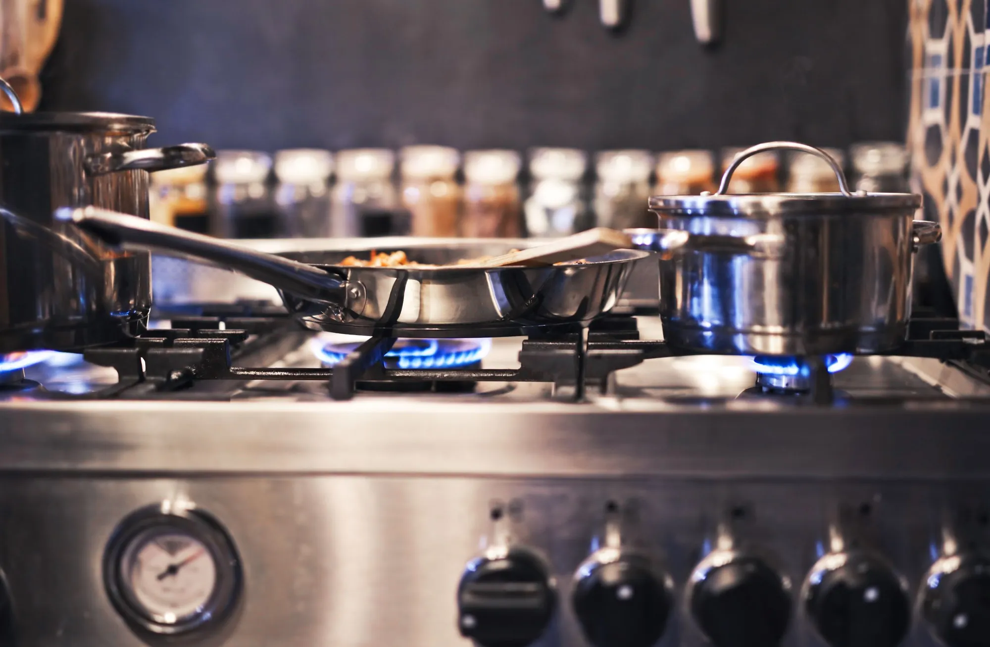 Pots on a stainless steel gas range with blue flames