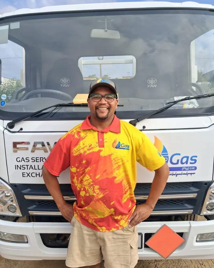 A WF Gas team member in the red and yellow uniform, in front of the gas truck